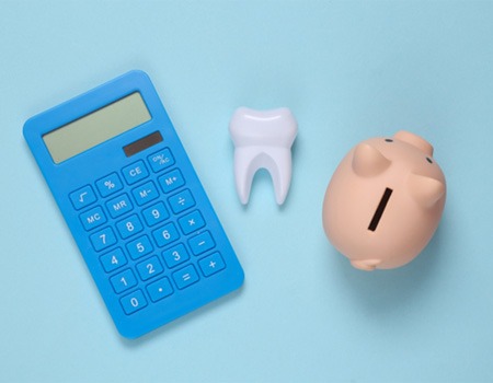 Piggy bank, calculator, and tooth against blue background