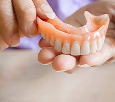 A close-up of hands holding a denture