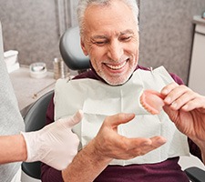 A dentist showing dentures to a senior patient