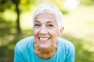 Woman with white hair in blue shirt outside smiling