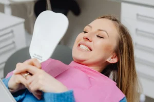 Woman looking at her teeth in hand mirror